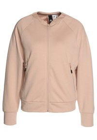 Sweat-shirt à fermeture éclair rose avec une texture côtelée, des manches raglan et deux poches latérales zippées. Comprend un col rond et des poignets élastiques.