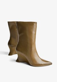 Botine din piele maro de tip wedge cu vârful ascuțit și textură netedă, având un fermoar la spate și un design de toc unghiular și conturat.