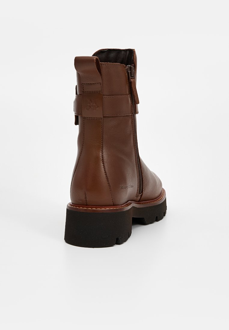 Braune Leder-Ankle-Boots mit strukturiertem Finish, seitlichem Reißverschluss und einer klobigen schwarzen Gummisohle. Genähte Akzente entlang des Randes.