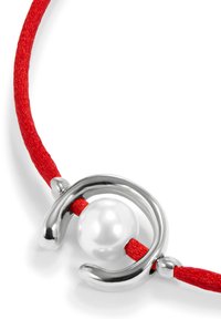 Collar de cordón rojo con un cierre de plata brillante y una perla blanca central, adornado con acentos metálicos curvados alrededor de la perla.