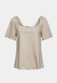 Blouse beige à manches courtes avec encolure carrée et épaules bouffantes, avec un petit détail de nœud au col arrière.