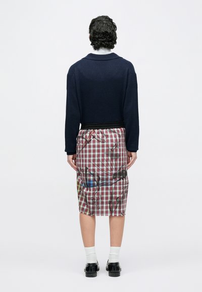 Pull en laine bleu marine avec col rond, assorti à une jupe à carreaux longueur genou, présentant un imprimé graphique et une taille élastique.