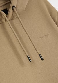 Jasnobrązowa bluza z kapturem, wykonana z miękkiego materiału, z dużym kapturem, czarnymi sznurkami do regulacji oraz subtelnym detalem w formie wytłoczonego logo.