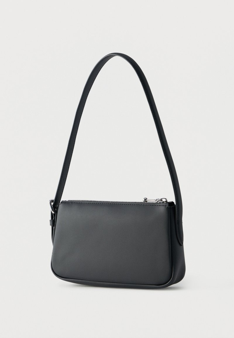 Schwarze Schultertasche mit Textur, einem einzelnen Riemen und einem silbernen Reißverschluss oben, dargestellt vor einem schlichten hellen Hintergrund.