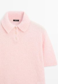 Světle růžová pletená polo košile s jemnou texturou, krátkými rukávy, třemi knoflíky a klasickým límečkem. Štítek viditelný na výstřihu.