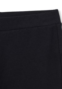 Leggings de algodón negros con una textura suave y lisa, cinturilla elástica ancha y un diseño ajustado sin patrones ni acentos visibles.