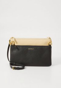 Black and beige leather crossbody bag with a textured surface, zipper closure, gold hardware, and adjustable strap. Brand name embossed on front.