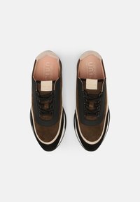 Brązowe zamszowe trampki z czarnymi skórzanymi akcentami, okrągły czubek i płaskie sznurówki. Posiadają beżową gumową podeszwę oraz subtelne logo na wkładce.