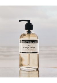 Klar pumpflaska med Marie-Stella-Maris Voyage Vétiver handtvål, ljus bärnstenfärgad vätska, etikett med doftbeskrivning av vetiver, salvia och havssalt.