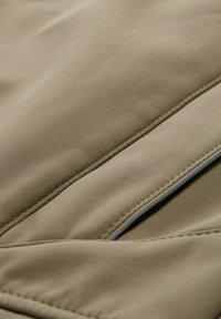 Beige textured fabric with a smooth finish, featuring stitched panels and a thin accent line. The material offers a soft appearance.