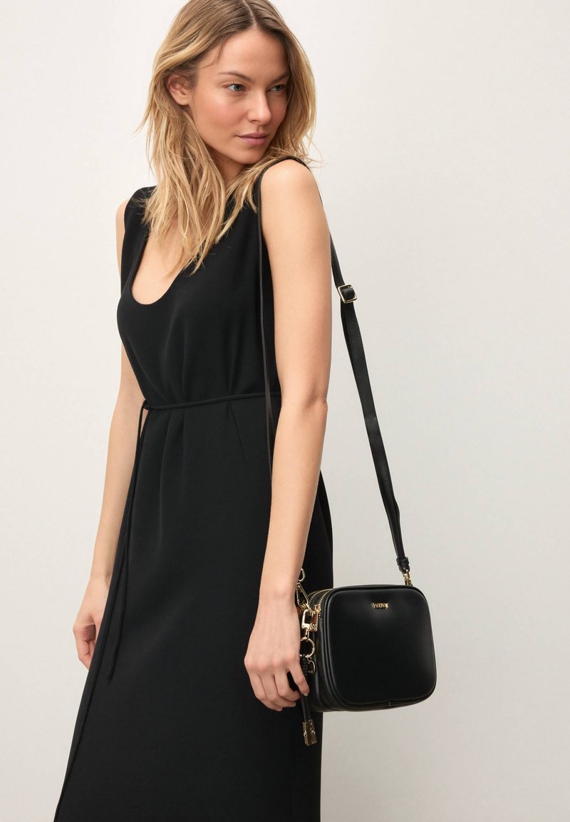 Must ristkott ruudukujulise kujuga, nahkmaterjalist ja kuldse riistvaraga. Omab tõmbluku sulgemist ning eemaldatavat õlarihma.