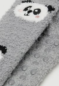 Calze grigie pelose con design di volto di panda, con accenti in bianco e nero, tessuto testurizzato e puntini in gomma sul fondo per una presa antiscivolo.