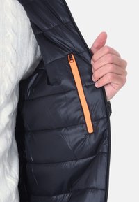 Gilet imbottito blu navy con texture trapuntata, caratterizzato da una tasca con zip arancione sul lato sinistro e chiusura a zip completa.