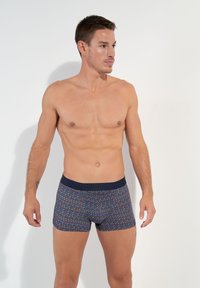 Boxer shorts in a multicolored zigzag pattern with a navy waistband. Made of elastic fabric, they feature a snug cut and soft texture.