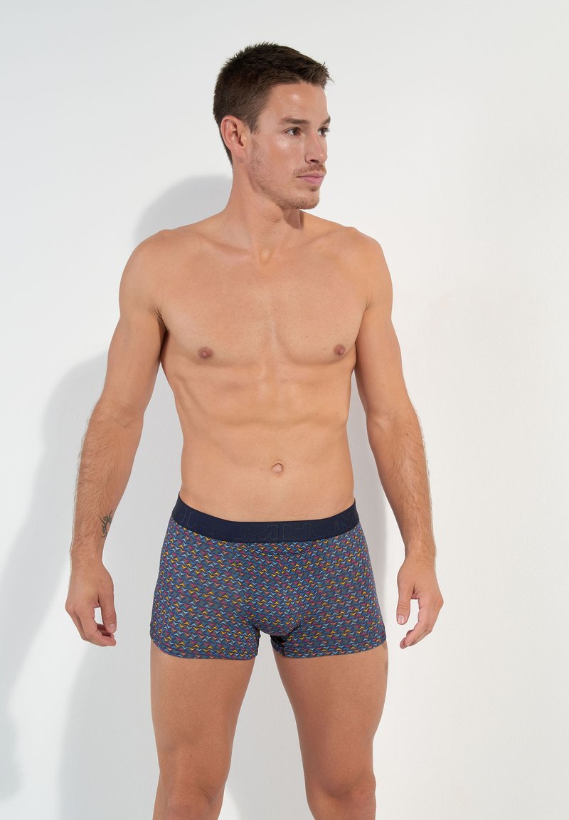 Boxer shorts in a multicolored zigzag pattern with a navy waistband. Made of elastic fabric, they feature a snug cut and soft texture.