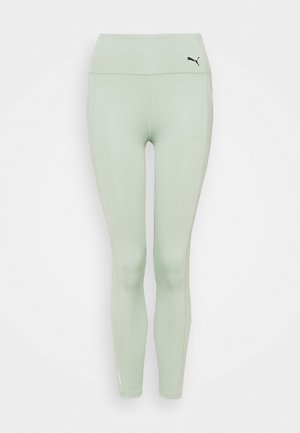 Leggings de sport vert clair en matière extensible, avec une taille haute, des poches latérales et un petit logo noir près de la taille.