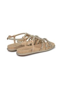 Beżowe sandały z paskowym wzorem, ozdobione metalicznymi akcentami i kamieniami, z płaskimi podeszwami i zapięciem na kostkę dla pewnego dopasowania.