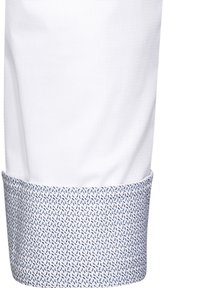 Camicia bianca con tessuto testurizzato e un polsino caratterizzato da un motivo astratto blu, in contrasto con il colore uniforme della camicia principale.