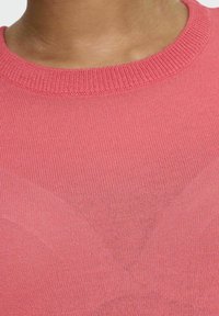 Suéter de color coral claro con un cuello redondo clásico, confeccionado en un tejido de punto ligero, que presenta una textura fina y un acabado de costura uniforme.