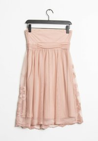 Blushfärgad axelbandslös klänning med skräddad bodice, lager av tyllekjol och spetsdetaljer i fållen. Hänger från en svart plastgalge.