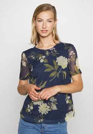 Blusa floral em azul marinho com mangas curtas, apresentando um tecido transparente, grandes padrões de flores verdes e amarelas, e um decote redondo.
