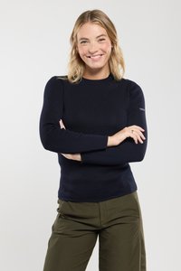 Navyblauw ribgebreid long-sleeve top met een ronde halslijn en subtiele schouderdetails, gecombineerd met olijfgroene broek.