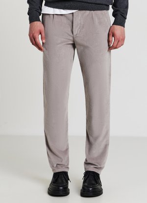 Pantaloni in corduroy grigio chiaro con una sottile trama a righe, dotati di tasche anteriori e una vestibilità rilassata, abbinati a scarpe nere con lacci.
