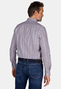 Heren overhemd met lange mouwen in het wit met een kleurrijk stippenpatroon; katoenmengsel; klassieke kraag; rechte snit; gestyled met blauwe jeans.
