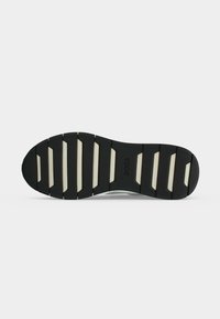 Semelle de chaussure avec une bande de roulement en caoutchouc noir et des rainures rectangulaires blanches, avec le logo "BOSS" au centre.