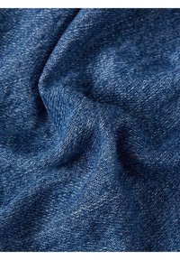 Pamuts denim szövet különböző kék árnyalatokban, amely textúrált szövést, látható varrásokat és puha esést mutat.