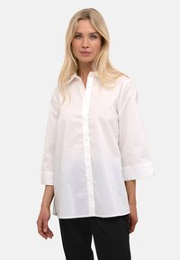 Camicia bianca con maniche a tre quarti, realizzata in cotone leggero, dotata di colletto classico e vestibilità comoda.
