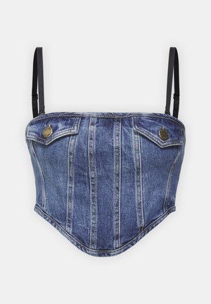 Denim korsete topi ar gaiši zilu audumu, strukturētu dizainu, divām krūšu kabatām un regulējamām melnām siksnām. Zelta krāsas aksesuāri.