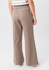 Beige wijde pantalons met een elastische tailleband, zijzakken en een gladde stoftextuur. De zoom is afgewerkt met een nette rand.