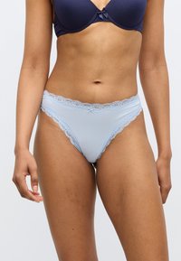 Culottes bleu clair bordées de dentelle, présentant une texture douce, une taille basse et des détails complexes le long de la ceinture et des ouvertures des jambes.