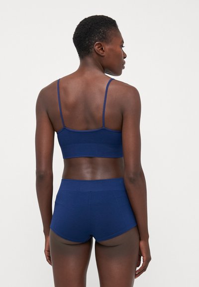 Navyblauwe geribbelde bralette met dunne bandjes en bijpassende high-waisted shorts, met een gladde textuur en een aangesloten ontwerp.