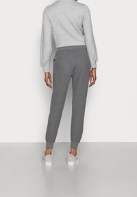 Grijze geribbelde joggers met een taps toelopende pasvorm, elastische tailleband en zijzakken, gecombineerd met lichtgekleurde casual schoenen.