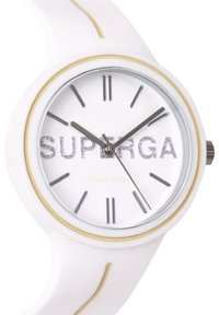 Reloj de silicona blanca con esfera redonda, manecillas plateadas y acentos metálicos. Logo "SUPERGA" en purpurina en la esfera. Diseño minimalista.