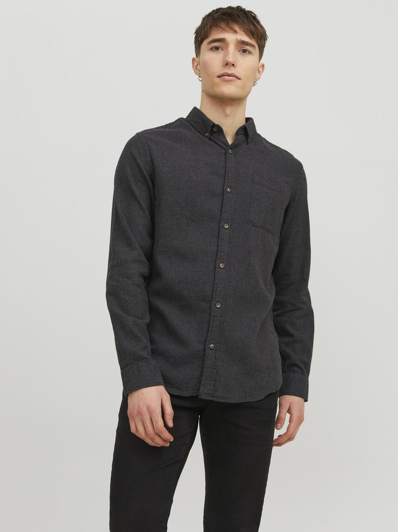 Camisa de botones gris oscuro hecha de tela texturizada, con un bolsillo en el pecho, mangas largas y cuello clásico. Acentuada con botones marrones.