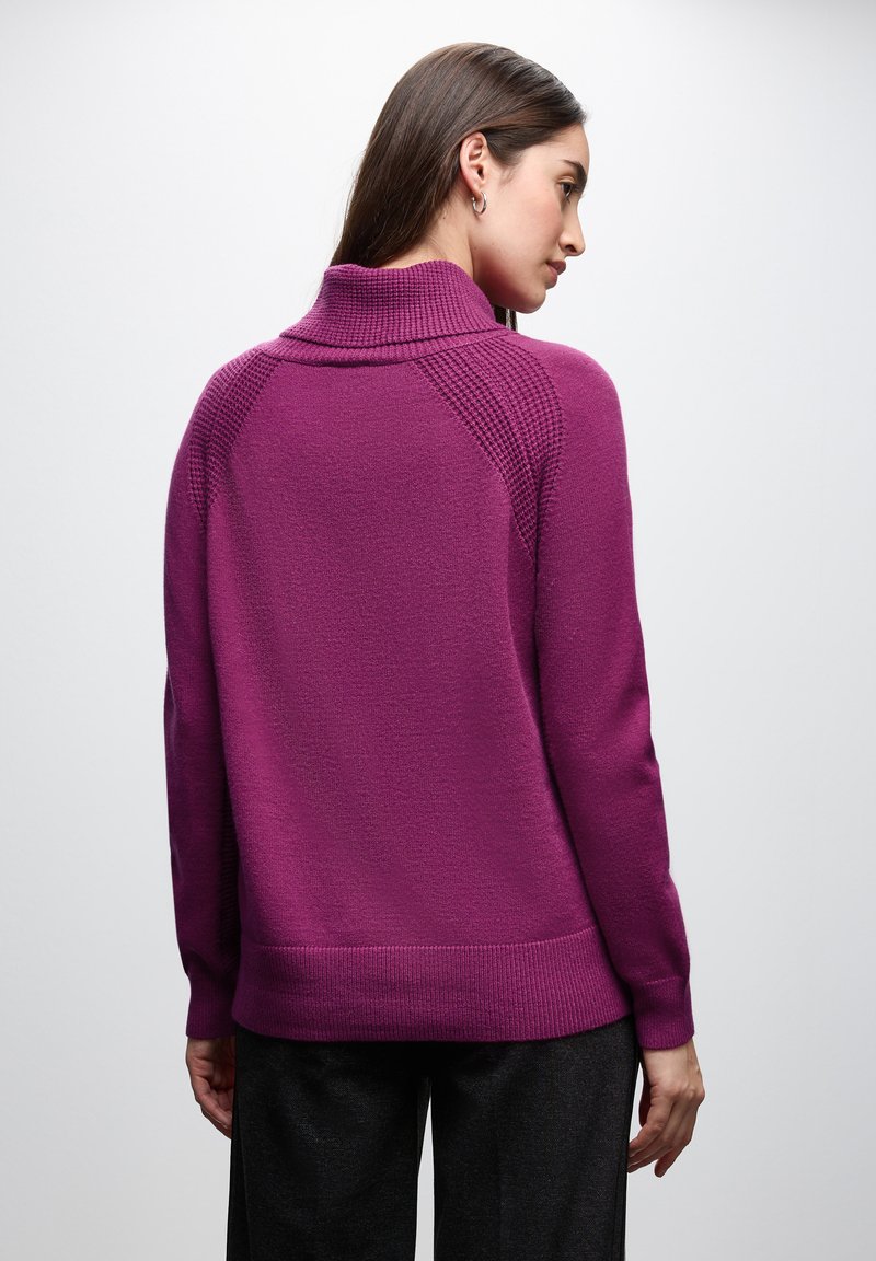 Fialový svetr s žebrovým rolákem; má texturované ramenní akcenty a uvolněný střih. Měkký materiál s hladkým povrchem.