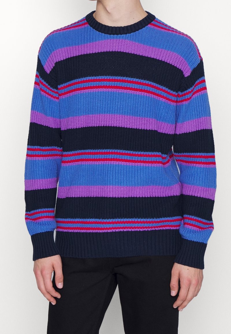 Stickad tröja med horisontella ränder i blått, lila och röd, med rundad hals och ribbade muddar och nederkant. Texturerad tyg.