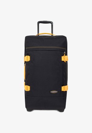 Valigia nera con ruote e dettagli gialli. Presenta una maniglia retrattile, due fibbie laterali, un ampio scomparto principale e un esterno in tessuto resistente.