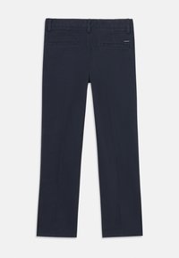 Navy blue chinos made of cotton with straight legs, two back pockets, and subtle branding detail near the waistband.