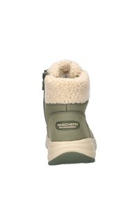 Waterdichte groene laars met een crèmekleurige faux fur kraag, een rits aan de zijkant en een beige zool. Bevat een logo patch van Skechers op de hiel.