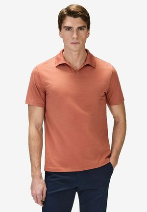 Kortærmet polo skjorte i terracotta med en afslappet krave, en glat tekstur og en tætsiddende form, parret med mørkeblå bukser.