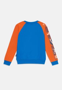 Modra in oranžna pulover s raglan rukavi, ki vsebuje grafični dizajn na desnem rukavu ter rebraste manšete in spodnji rob.