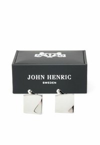 Fyrkantiga silvercufflinks med en polerad yta och lätt böjda accenter, presenterade i en svart box med vitt logotyp och text.