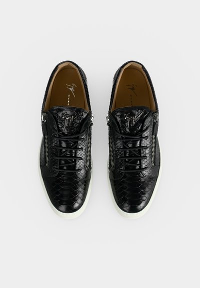 Μαύρα sneakers με υφή δερματίνης φιδιού, χαμηλού τύπου, λευκές σόλες, πλαϊνά φερμουάρ, κορδόνια και λογότυπο σχεδιαστή στη γλώσσα και τις εσωτερικές σόλες.