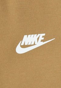 Tessuto in maglia marrone con un prominente logo Nike bianco in design a swoosh. La texture è liscia con un motivo di maglia coerente.