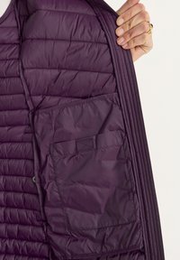 Paarse opblaasbare vest met horizontale stitching aan de binnenkant, voorzien van een grote zak. Gladde, glanzende stof met een iets glanzende textuur.