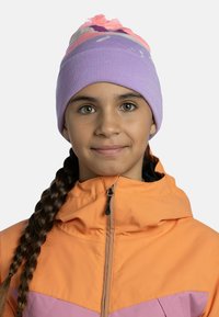 Purple knit beanie with pink accents and a pom-pom on top, worn with an orange and pink zip jacket featuring a high collar.